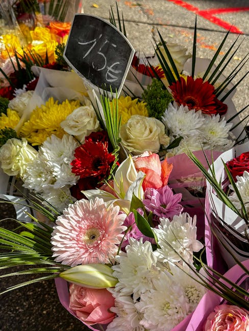 A vibrant bouquet arrangement featuring a mix of fresh flowers including large white roses, pink gerbera daisies, red gerbera daisies, and white lilies, all artistically arranged with long green palm